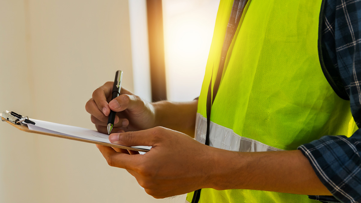 Close up hands of inspector wear safety vest and checking list